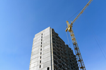 Construction of a multi-storey building. High-rise construction crane. Blue sky.