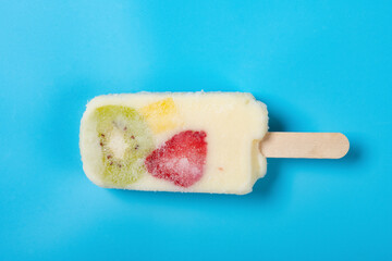 top view fresh yogurt flavor popsicle with slices of kiwi and mango and strawberry on blue background