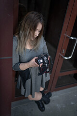 A curvy photographer girl in a gray short dress, leather platform boots and with a camera in her hands looks through the material taken at the photo shoot on the camera screen