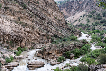 A rugged mountain landscape in a desert region of Iran, showcasing rocky terrain and sparse vegetation under a clear sky.
