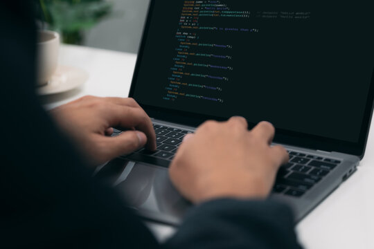 Closeup of a man's hands coding HTML and programming on a laptop screen, web development, developer.