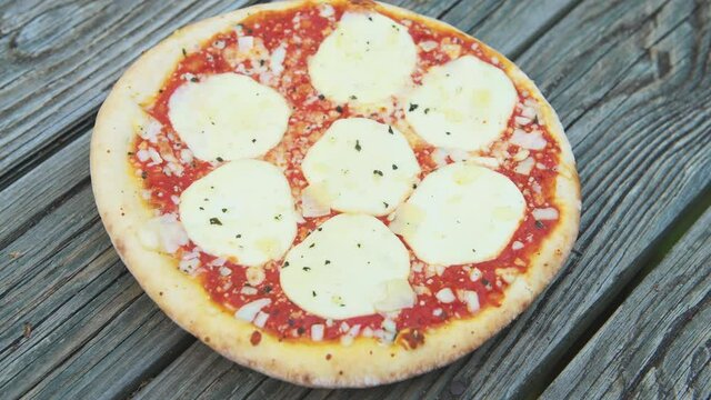 Fresh crust whole small pizza on table with melted mozzarella cheese and sprinkles and red tomato sauce closeup as Italian food cuisine
