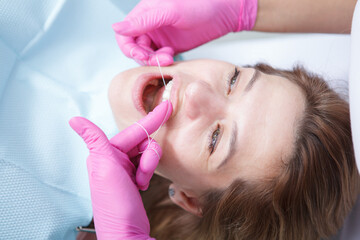 Unrecognizable dentist flossing teeth of female patient