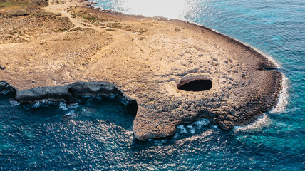 Aerial view of Ahrax fallen cave,Coral Lagoon,Malta.Hole in the middle of rocks with crystal clear water inside.Rocky Maltese coast.Perfect spot for diving.Vacation in Mediterranean,travel Europe.