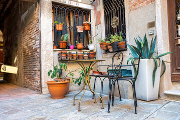 Traditional house with potted plants on brick walled window with chairs and tables at the outdoors