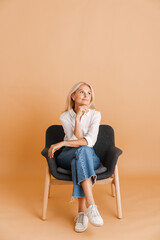Mature blonde woman looking aside while sitting in chair