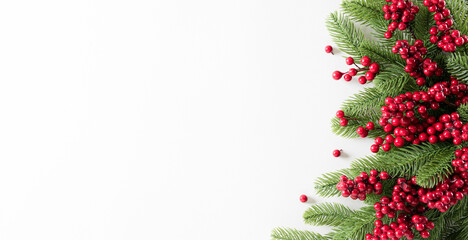Christmas background concept. Top view of pine branches and red berries on white background.