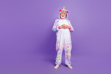 Photo of cool dreamy retired man nightwear overall smiling arms stomach looking empty space isolated purple color background
