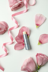 Obraz na płótnie Canvas Hygienic lipstick and roses on white background