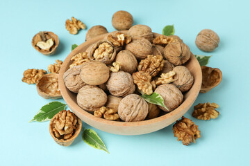 Walnuts in wooden bowl on blue background