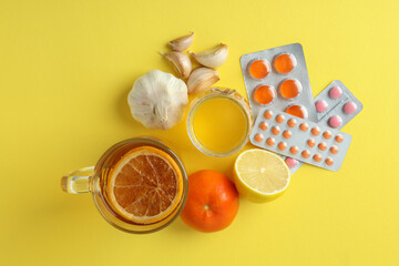 Concept of treatment colds with honey and garlic on yellow background