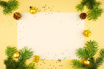 New Year composition on yellow background. Christmas white background with  golden  balls and fir branches. Top view, copy space, flat lay.