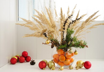 Christmas natural spruce bouquet  with dry decor and pampas  in  vase on white windowsill by the window.  Fir decorations at home winter.  New Year concept. 
