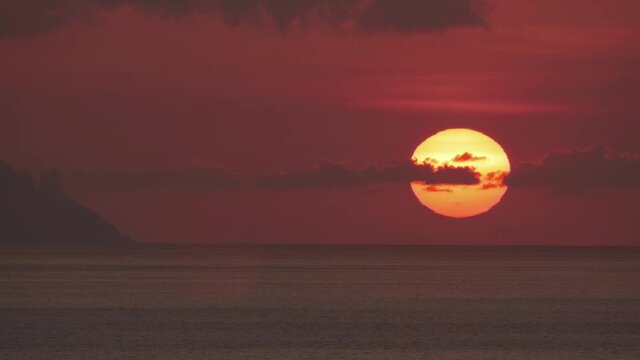 A magnificent mystical blood-red sea sunset. A huge southern sun sits behind the ocean horizon