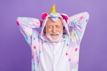 Portrait of attractive cheerful dreamy grey-haired man wearing kigurumi resting isolated over violet purple color background