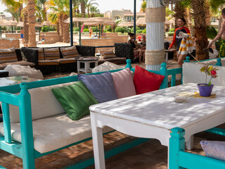 Hurghada, Egypt - September 22, 2021: Beach bar near the red sea. People sit on sofas with colorful pillows and drink cocktails.