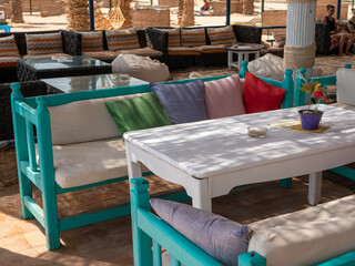 Hurghada, Egypt - September 22, 2021: Beach bar near the red sea. The multi-colored sofas with colorful cushions are sheltered in the shade. Side view.