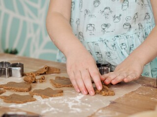 Close-up of children's hands cutting ginger cookies out of dough. Little girl making Christmas cookies. Christmas holidays, moments