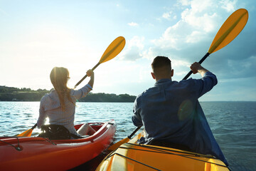 Beautiful couple kayaking on river, back view. Summer activity