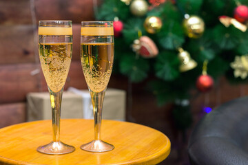 Two glasses of champagne on the background of a Christmas tree. A game of bubbles in a glass of wine. Copy space