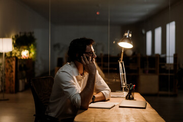 White bearded man talking on cellphone while working at office