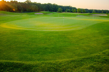 Green golf course at sunset.