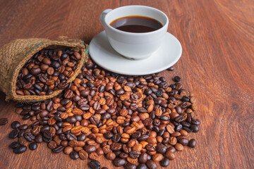 cup of coffee and coffee beans in a sack on Brown background