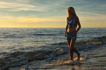 woman walking on the beach at sunset in shorts
