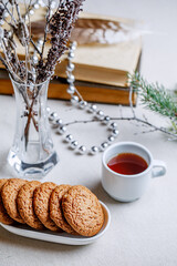 Homemade oatmeal cookies on a white plate. Winter composition for the interior. A healthy breakfast with cereal cookies and tea.