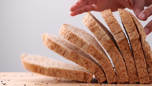 Close up whole wheat multigrain bread sliced falling on wooden table on white background, slow motion. Loaf of Bread, Slice of food, Healthy Food Concept.