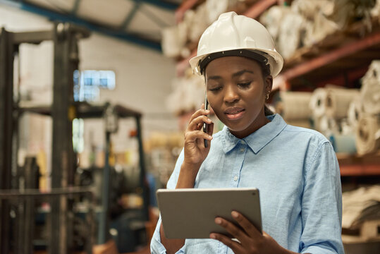 African woman with a tablet and phone at work in a warehouse