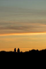 Fototapeta na wymiar Human female silhouettes at sunset, scenery cloudscape
