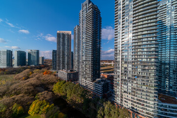 Fototapeta na wymiar Drone Views of condos and Humber bay shores with brown trees tops Fall colours by Parklawn rd and lakeshore with blue skies and broken clouds 