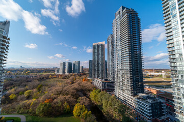 Obraz premium Drone Views of condos and Humber bay shores with brown trees tops Fall colours by Parklawn rd and lakeshore with blue skies and broken clouds 