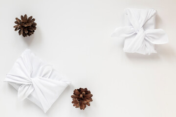 Furoshiki is a traditional Japanese tying technique. White gifts with cones. Ecological gift wrapping. the concept of waste-free use of gift wrapping. Bojagi.