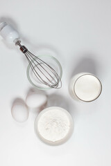Baking ingredients on white table. White eggs, flour, sugar. Home concept for baking, baking cake or biscuit ingredients