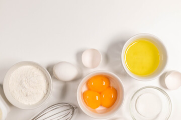 Dessert ingredients and dishes on a light pastel background. Flat lay with eggs, flour, sugar, cottage cheese