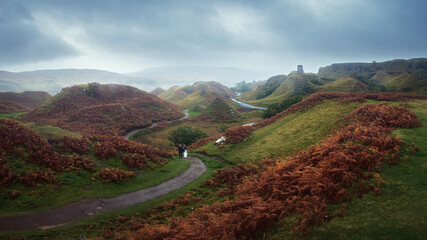 Landscape view of mountains with path and couple from the back. Fairy Glen on Isle of Skye,...