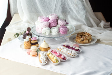 Fototapeta na wymiar Traditional French desserts meringue, eclair, choux pastry, macaroon on a table in interior