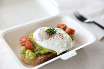 Poached eggs with avocado on toast with delivery package in white background