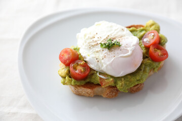 Poached eggs with avocado on toast in white background