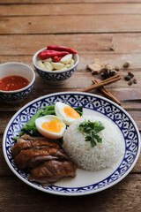 Local Thai food stewed pork leg on rice isolated in wood background