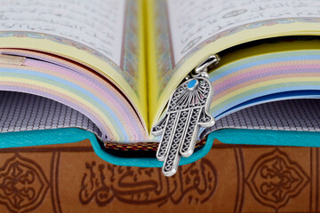 Open Holy Quran with Hamsa (Hand of Fatima) symbols of Muslim faith and religion, France