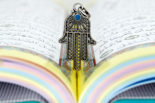 Open Holy Quran with Hamsa (Hand of Fatima) symbols of Muslim faith and religion, France