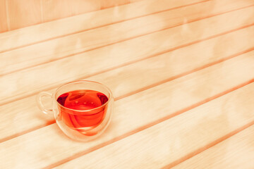 Glass cup with tea and steam on the shelf in the sauna. Tea drinking in the sauna and bath.