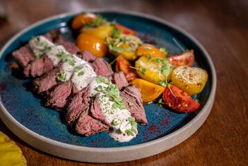 Elegant and delicious food on restaurant. Plate with tasty meal on the wooden table. Gourmet cuisine, lunch, dinner, beautiful, modern. Steak is grilled sliced on a pieces with vegetables