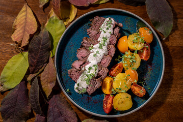 Elegant and delicious food on restaurant. Plate with tasty meal on the wooden table. Gourmet cuisine, lunch, dinner, beautiful, modern. Steak is grilled sliced on a pieces with vegetables