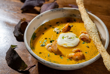 Traditional pumpkin сreamy soup with shrimps and spices on wooden table. Fall  concept. Copy space.