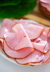 Ham slices on a white plate on kitchen table