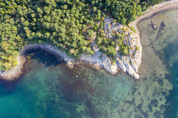 Aerial view of a rocky coastline and forested cliffs meeting the Norwegian sea.